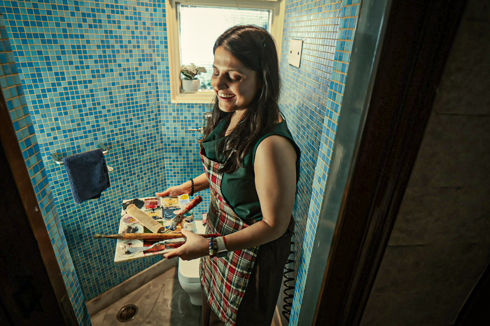 Shivani Garg seated with materials in her turquoise-walled studio