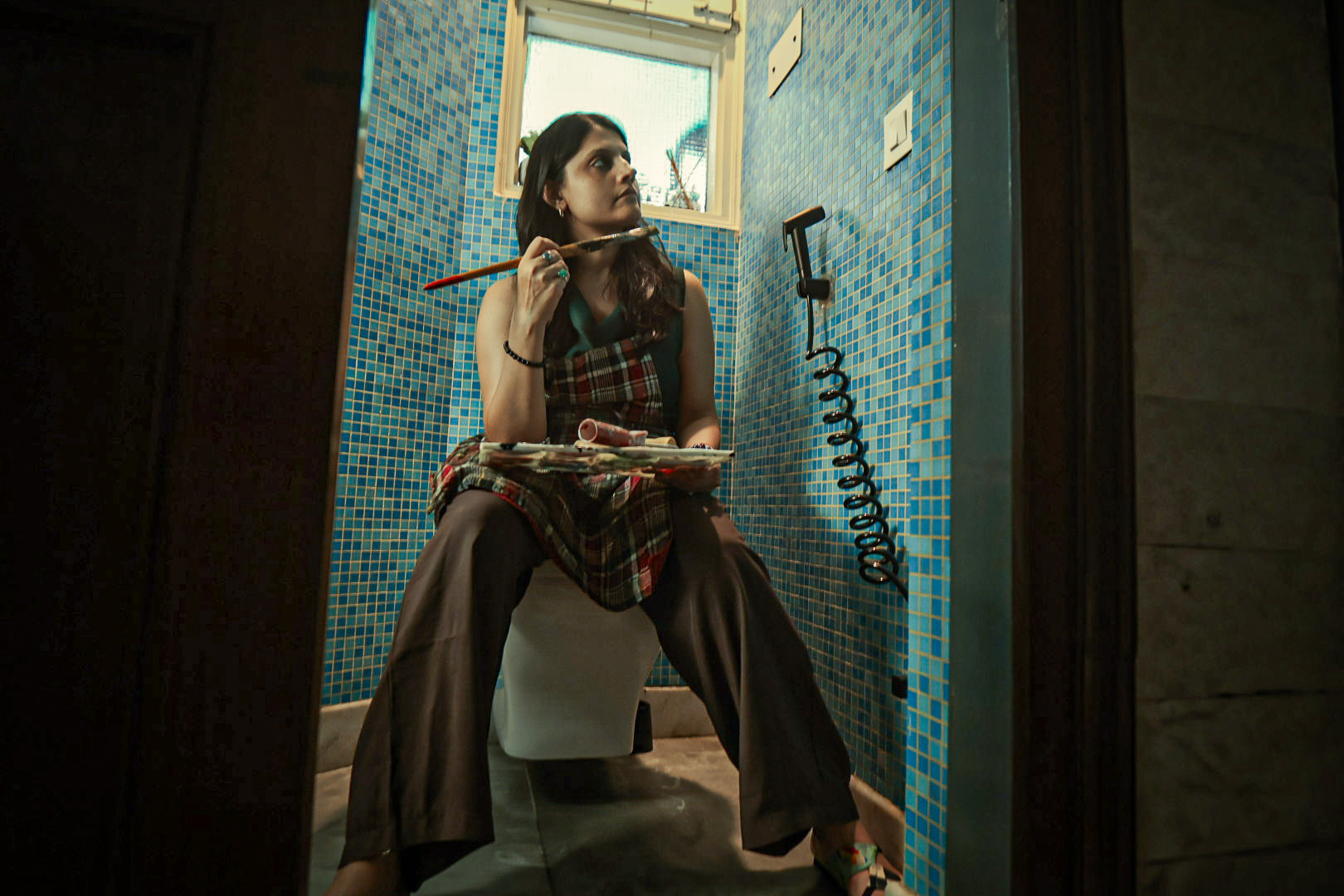 Shivani Garg seated with a brush held to her face and a palette on her lap