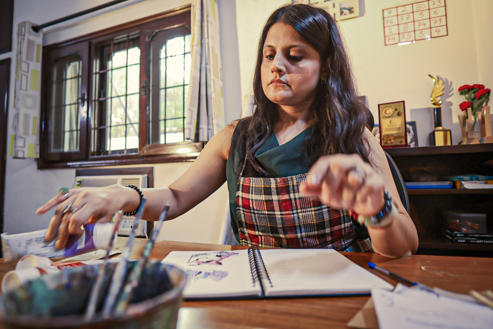 Shivani Garg reaching across the studio desk to choose a colour