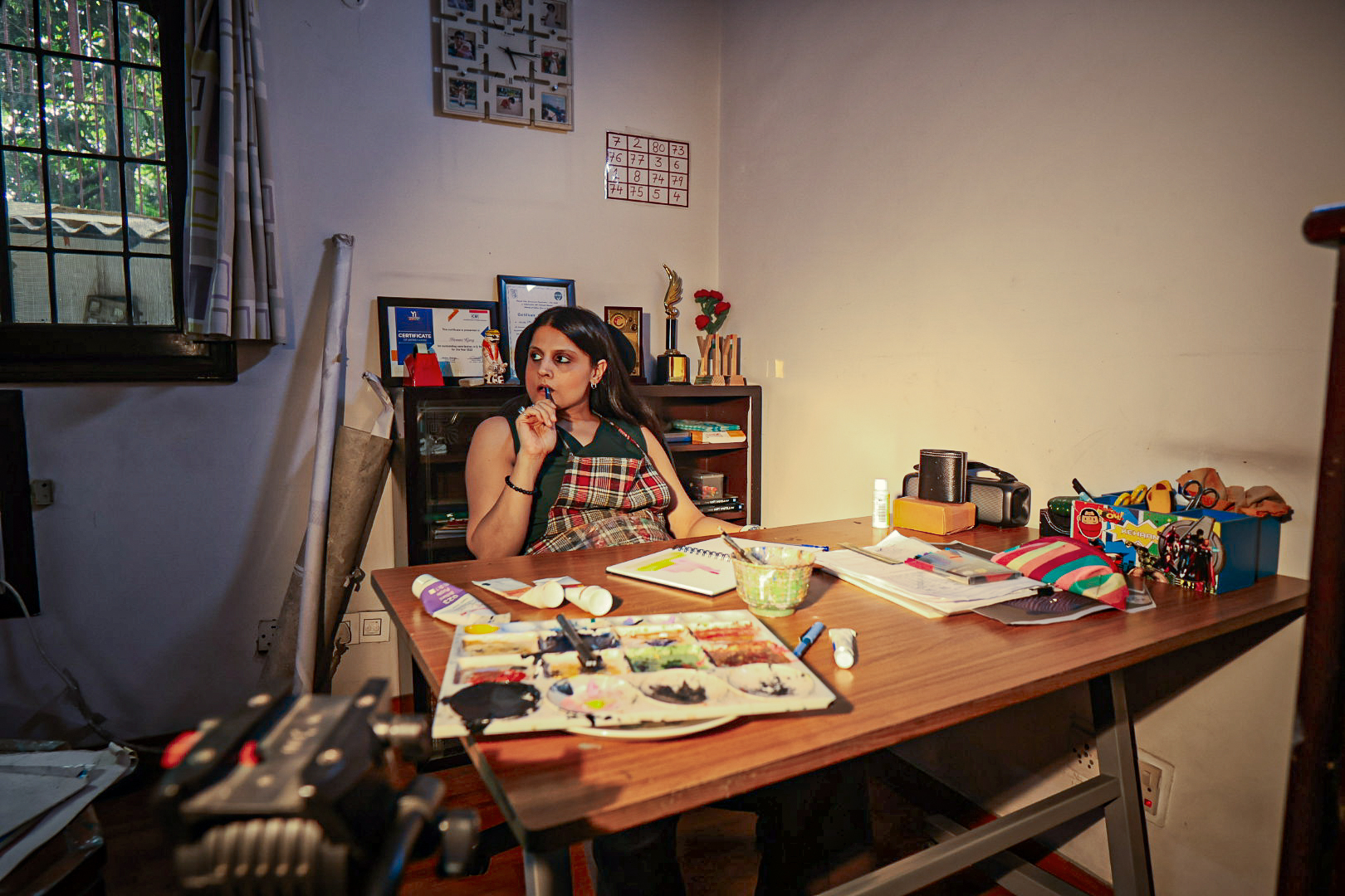 Shivani Garg seated at a table covered in colour and paper
